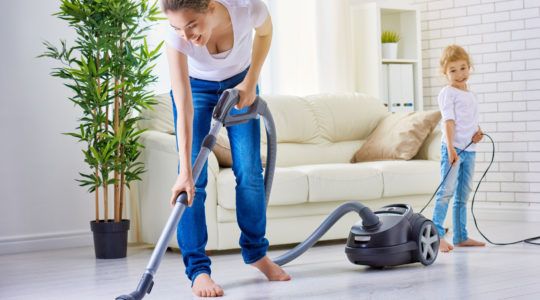 Woman vacuuming a floor with her child